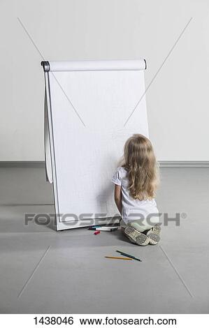 Stock Photograph - Rear view of girl drawing on flipchart against white wall. Fotosearch