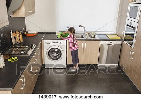 Rear view of girl washing dishes in kitchen View Large Photo Image Stock Photo - Rear view of girl washing dishes in kitchen. Fotosearch