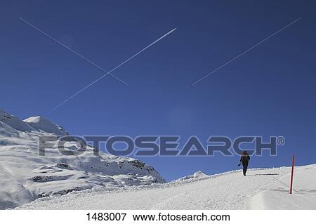 Rear view of person hiking on snow covered mountain against blue sky View Large Photo Image Stock Photo - Rear view of person hiking on snow covered mountain against blue sky. Fotosearch