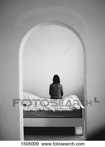 Rear view of woman sitting on a bed View Large Photo Image Stock Photo - Rear view of woman sitting on a bed. Fotosearch