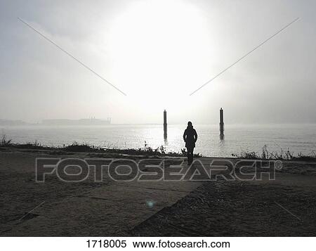 Rear view of woman standing on boardwalk by sea against sky, Hamburg, Germany View Large Photo Image Stock Photography - Rear view of woman standing on boardwalk by sea against sky, Hamburg, Germany. Fotosearch