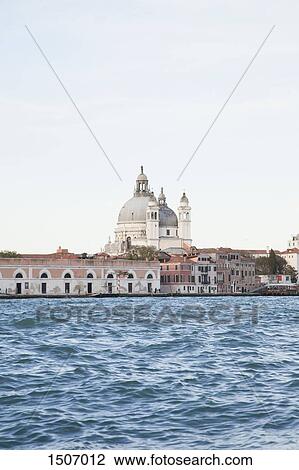 Stock Image - Santa Maria della Salute and buildings by canal against cleat sky. Fotosearch