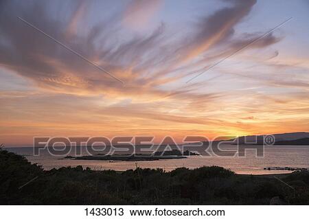 Stock Image - Scenic view of sea against cloudy sky during sunset. Fotosearch