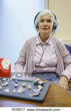 Stock Photo - Senior patient wearing headphones during hearing test while sitting at clinic. Fotosearch