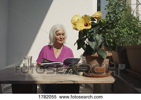 Senior woman reading magazine on sunny patio View Large Photo Image Stock Photography - Senior woman reading magazine on sunny patio. Fotosearch
