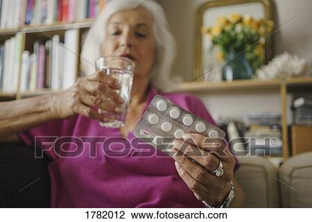 Stock Image - Senior woman taking medication. Fotosearch