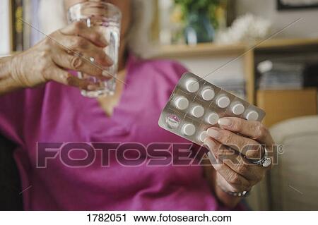 Stock Image - Senior woman taking medication. Fotosearch