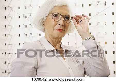 Senior woman wearing eyeglasses at store View Large Photo Image Stock Image - Senior woman wearing eyeglasses at store. Fotosearch