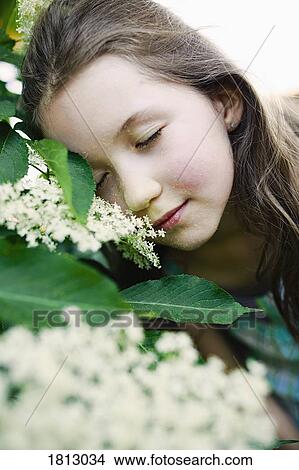 Picture - Serene girl leaning on blooming bush. Fotosearch