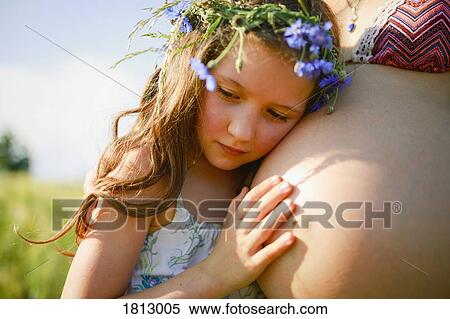 Serene girl with flowers in hair leaning on pregnant mothers stomach View Large Photo Image Stock Photography - Serene girl with flowers in hair leaning on pregnant mothers stomach. Fotosearch