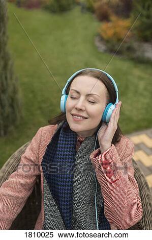 Stock Photography - Serene woman listening to music with headphones outside. Fotosearch