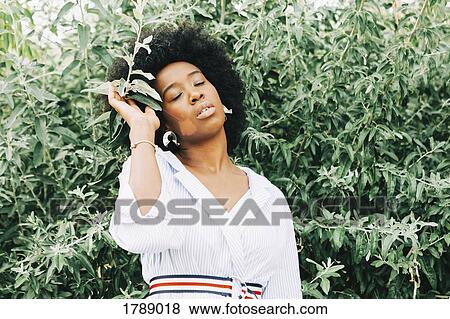 Serene woman standing at green bush View Large Photo Image Stock Photo - Serene woman standing at green bush. Fotosearch