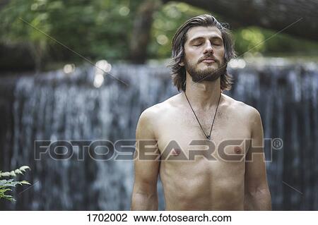 Shirtless young man with closed eyes standing against waterfall at forest View Large Photo Image Stock Image - Shirtless young man with closed eyes standing against waterfall at forest. Fotosearch