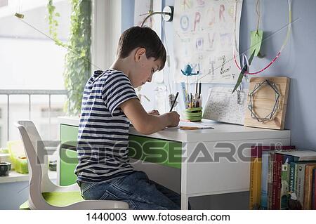Side view of boy doing homework at table in house View Large Photo Image Stock Image - Side view of boy doing homework at table in house. Fotosearch
