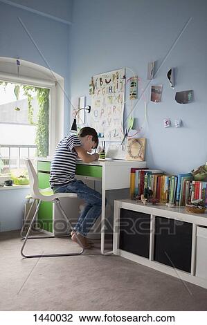 Side view of boy doing homework at table in house View Large Photo Image Stock Image - Side view of boy doing homework at table in house. Fotosearch