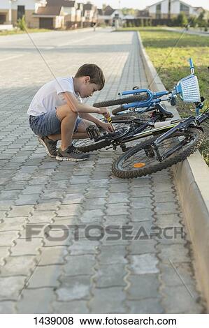 Side view of boy repairing bicycle on footpath View Large Photo Image Stock Photo - Side view of boy repairing bicycle on footpath. Fotosearch