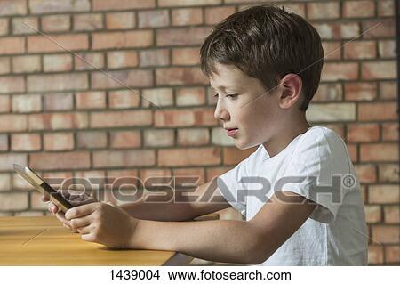 Picture - Side view of boy using digital tablet at home. Fotosearch