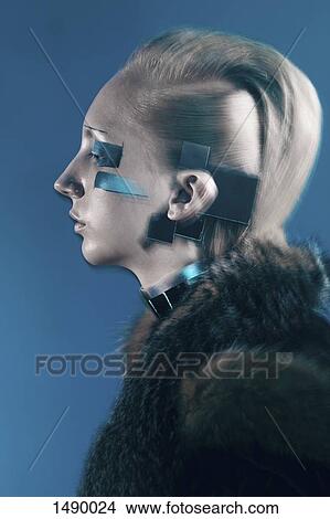 Picture - Side view of confident fashion model in fur coat against blue background. Fotosearch
