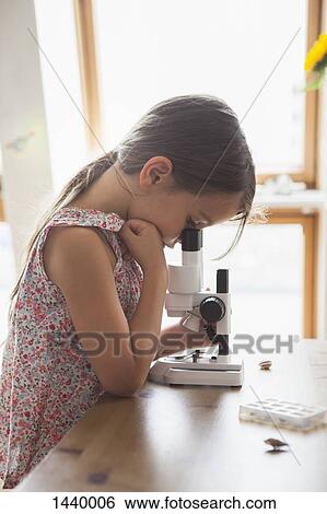 Side view of curious girl looking into microscope on table at home View Large Photo Image Stock Photograph - Side view of curious girl looking into microscope on table at home. Fotosearch