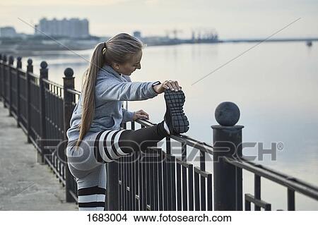 Side view of female athlete stretching by railing on footpath, Blagoveshchensk, Amur, Russia View Large Photo Image Picture - Side view of female athlete stretching by railing on footpath, Blagoveshchensk, Amur, Russia. Fotosearch