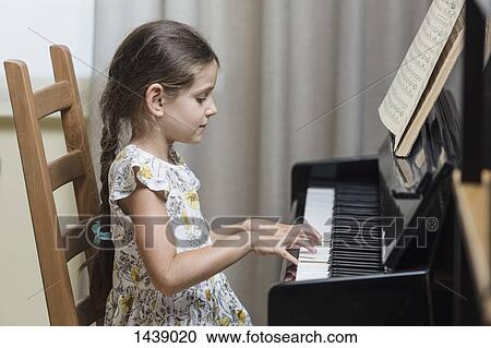 Side view of girl playing piano at home View Large Photo Image Stock Image - Side view of girl playing piano at home. Fotosearch