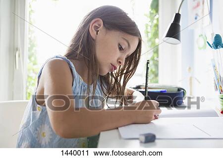 Side view of girl writing in book on table at home View Large Photo Image Stock Image - Side view of girl writing in book on table at home. Fotosearch
