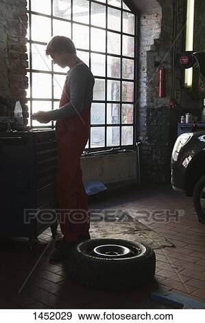 Side view of mechanic standing by window at garage View Large Photo Image Stock Photo - Side view of mechanic standing by window at garage. Fotosearch