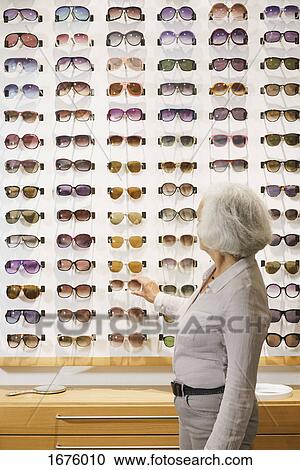Side view of senior woman choosing sunglasses at store View Large Photo Image Stock Image - Side view of senior woman choosing sunglasses at store. Fotosearch