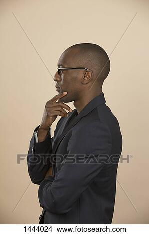 Side view of thoughtful man standing against colored background View Large Photo Image Picture - Side view of thoughtful man standing against colored background. Fotosearch