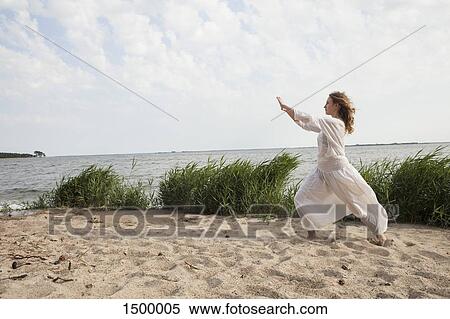 Side view of woman practicing yoga on sea shore against sky View Large Photo Image Stock Photography - Side view of woman practicing yoga on sea shore against sky. Fotosearch