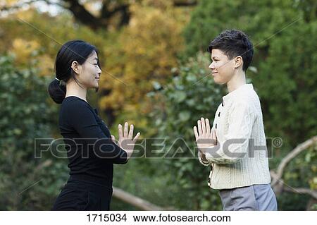Picture - Side view of women with hands clasped performing yoga against trees at park. Fotosearch
