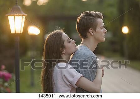Side view of young woman embracing boyfriend at park View Large Photo Image Stock Image - Side view of young woman embracing boyfriend at park. Fotosearch