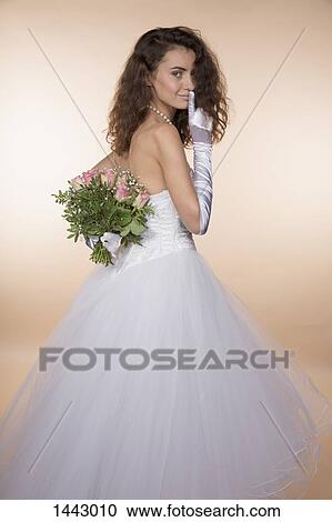 Side view portrait of bride showing silence gesture while hiding bouquet against colored background View Large Photo Image Stock Image - Side view portrait of bride showing silence gesture while hiding bouquet against colored background. Fotosearch
