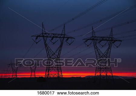 Stock Photo - Silhouette electricity pylons on field against sky at dusk. Fotosearch