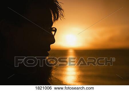 Silhouette profile teenage boy looking at sunset over ocean View Large Photo Image Stock Photograph - Silhouette profile teenage boy looking at sunset over ocean. Fotosearch