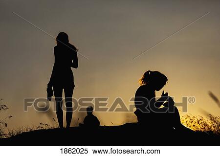 Silhouette women eating and drinking on hill at sunset View Large Photo Image Stock Photography - Silhouette women eating and drinking on hill at sunset. Fotosearch