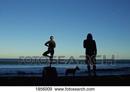 Silhouette young couple with dog practicing yoga on sunrise beach View Large Photo Image Stock Photo - Silhouette young couple with dog practicing yoga on sunrise beach. Fotosearch