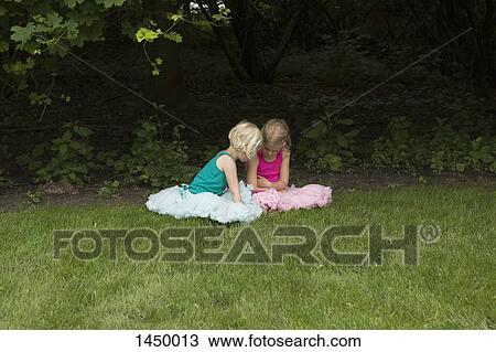 Sisters sitting on grassy field in backyard View Large Photo Image Stock Image - Sisters sitting on grassy field in backyard. Fotosearch