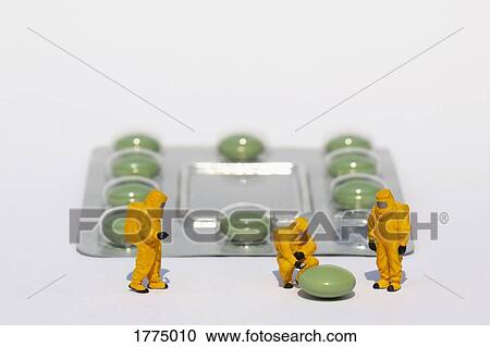 Stock Image - Small scientists in clean suits examining green pill from blister pack. Fotosearch