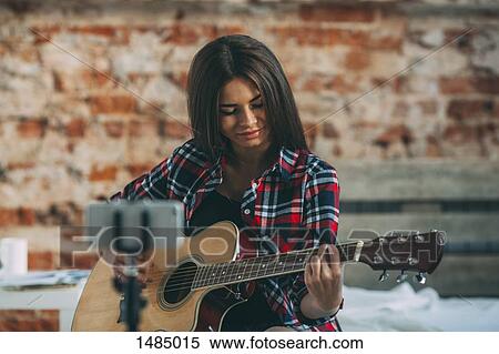 Smart phone in monopod with woman playing guitar at home View Large Photo Image Stock Photography - Smart phone in monopod with woman playing guitar at home. Fotosearch