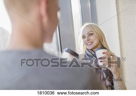 Stock Photograph - Smiling businesswoman drinking coffee with colleague in cafe. Fotosearch