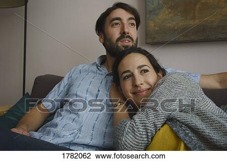 Smiling couple relaxing on living room sofa View Large Photo Image Stock Image - Smiling couple relaxing on living room sofa. Fotosearch