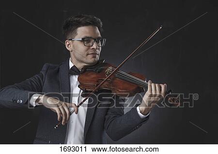 Smiling handsome violinist playing violin against black background View Large Photo Image Stock Image - Smiling handsome violinist playing violin against black background. Fotosearch