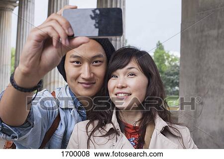 Stock Photo - Smiling man taking selfie with young female friend. Fotosearch