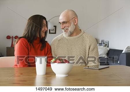 Smiling mature couple looking face to face while sitting at home View Large Photo Image Stock Photo - Smiling mature couple looking face to face while sitting at home. Fotosearch