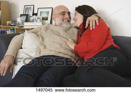 Smiling mature couple relaxing on sofa at home View Large Photo Image Stock Photography - Smiling mature couple relaxing on sofa at home. Fotosearch