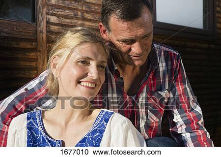 Smiling mature couple sitting outside farmhouse View Large Photo Image Stock Image - Smiling mature couple sitting outside farmhouse. Fotosearch