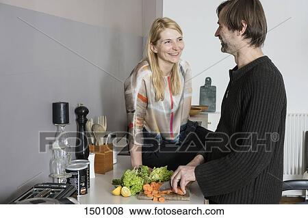 Smiling mature woman looking at man cutting vegetables in kitchen View Large Photo Image Stock Photo - Smiling mature woman looking at man cutting vegetables in kitchen. Fotosearch