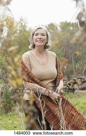 Smiling mature woman looking away while standing at park during autumn View Large Photo Image Stock Image - Smiling mature woman looking away while standing at park during autumn. Fotosearch