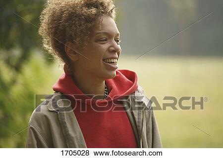 Smiling mid adult woman with curly hair looking away at park View Large Photo Image Stock Photo - Smiling mid adult woman with curly hair looking away at park. Fotosearch